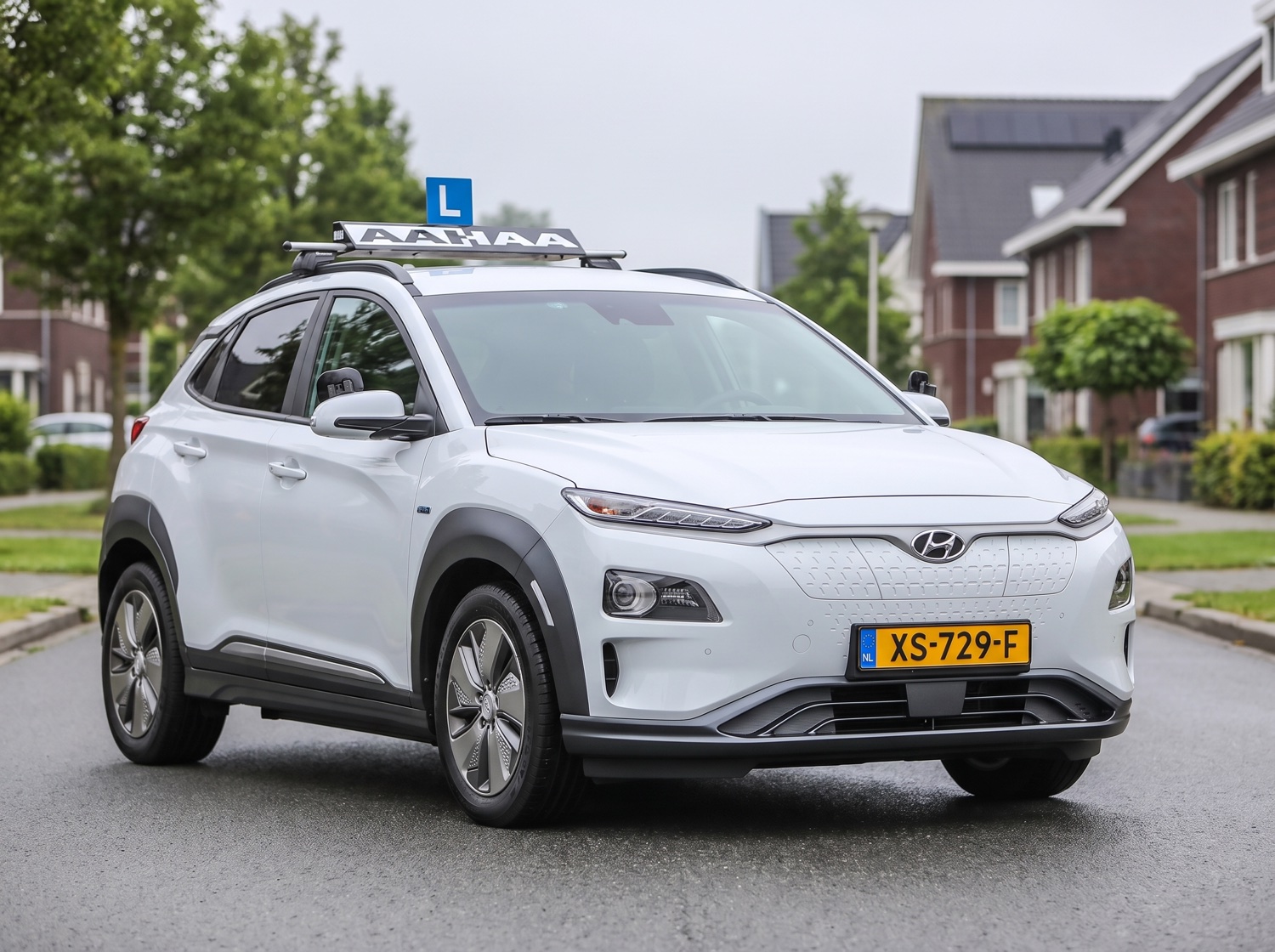 De witte Hyundai Kona lesauto van Rijschool AAHAA met het AAHAA-bord en L-plaat op het dak